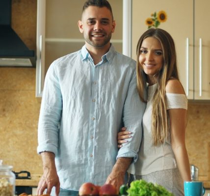 Portrait of loving couple cooking breakfast smiling ang looking into camera in the kitchen at home