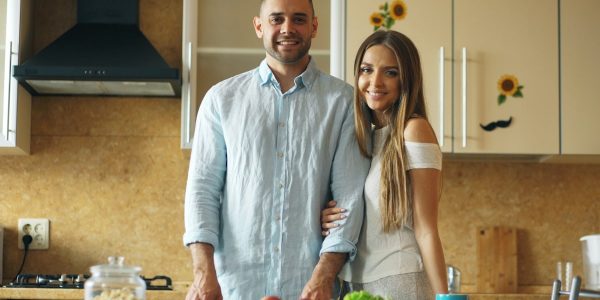 Portrait of loving couple cooking breakfast smiling ang looking into camera in the kitchen at home